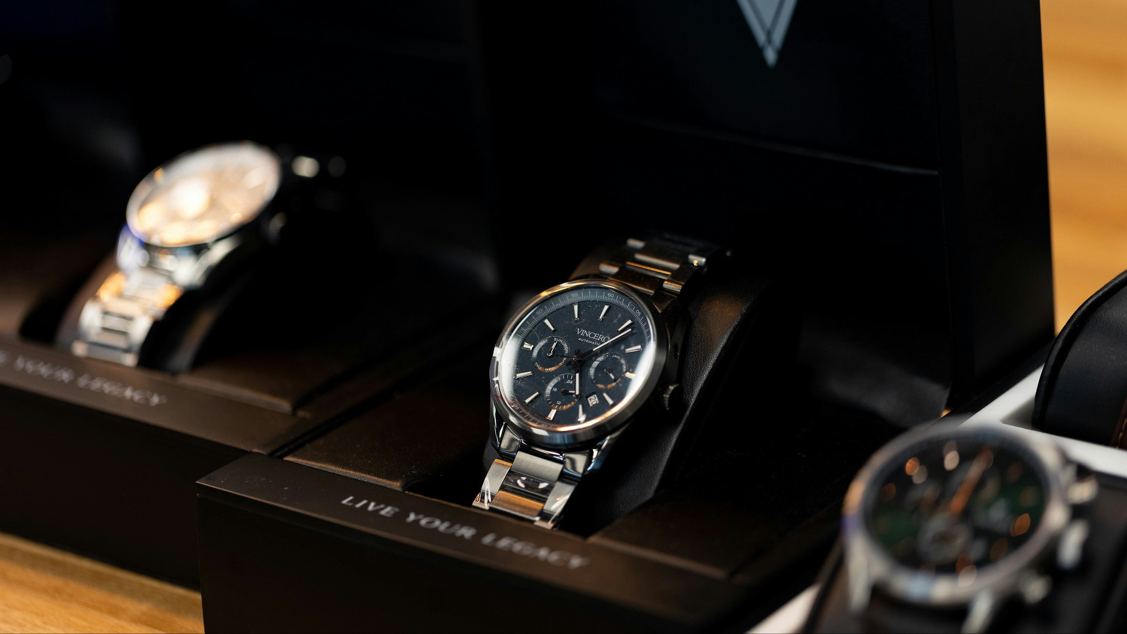 Three watches displayed on a wooden surface with a dark background